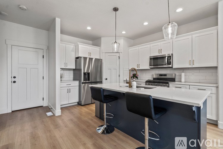A kitchen with white cabinets and a black island.