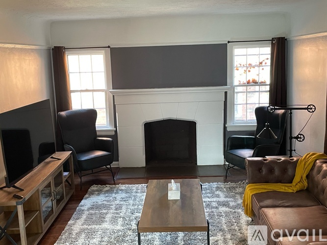 A living room with a fireplace, two chairs, a couch, and a coffee table.