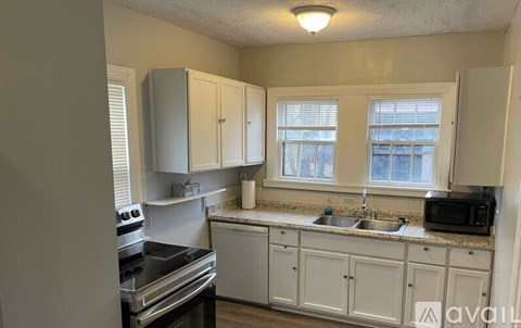 A kitchen with white cabinets and a black stove top.