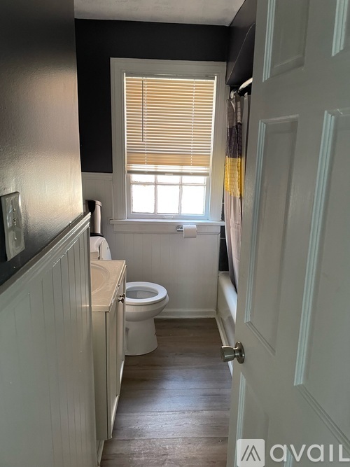 A bathroom with a toilet, sink, and window.