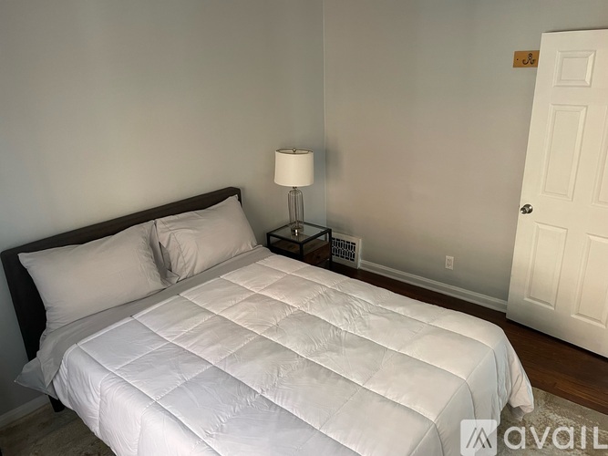 A white bed with a black headboard and a white comforter.