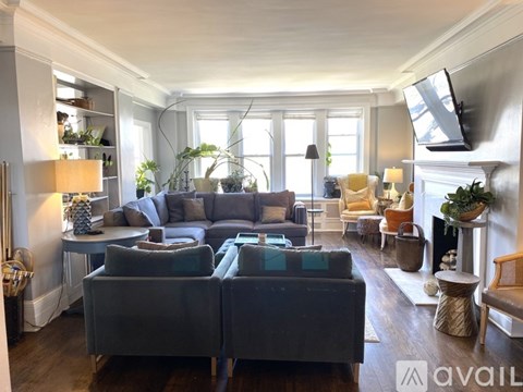 A living room with a grey couch and a fireplace.