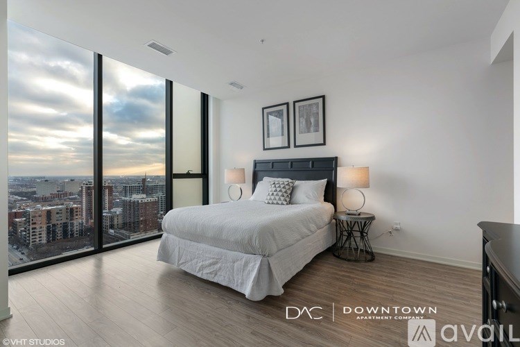 A bedroom with a large bed and a view of the city through the windows.