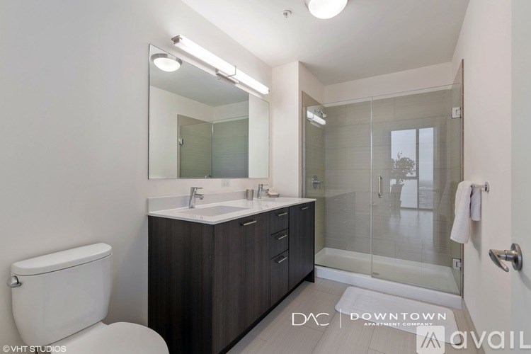 A bathroom with a toilet, sink, mirror, and glass shower door.