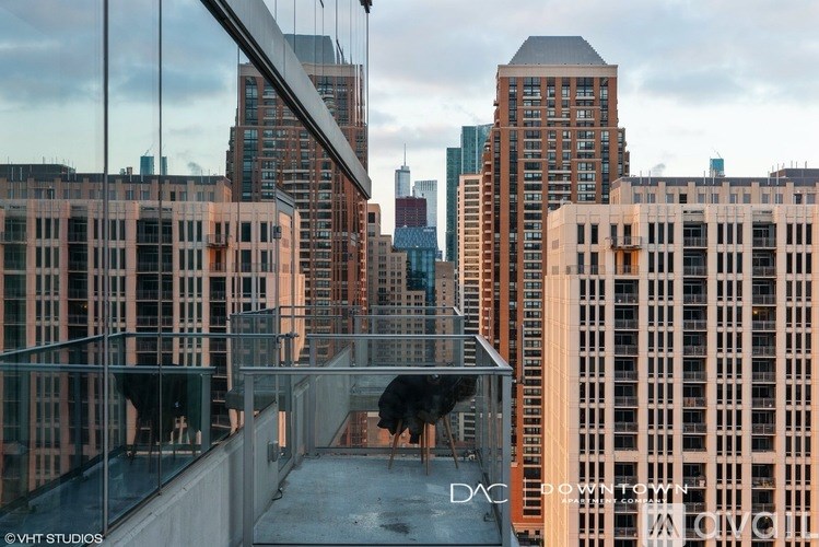 A glass enclosed walkway with a chair and table in the middle of it.