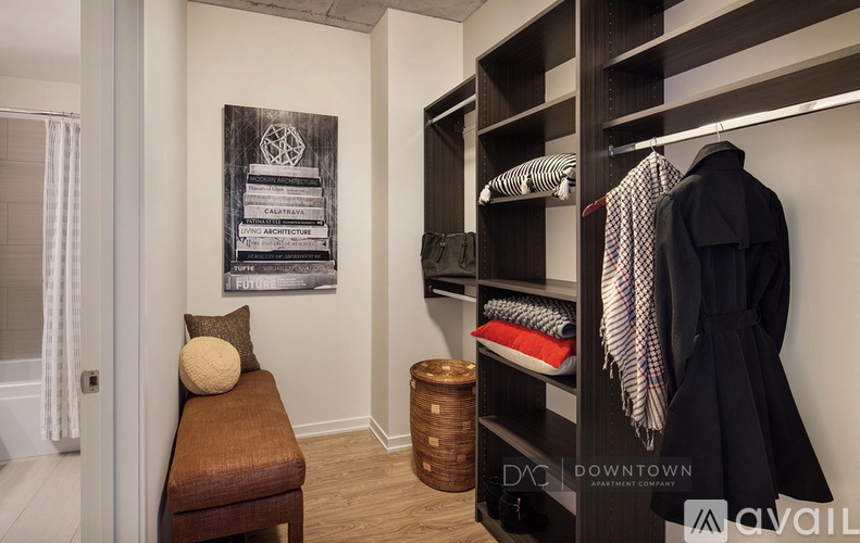 A room with a bench, a coat hanging on a rack, and a basket on the floor.