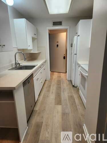 A kitchen with white cabinets and a wooden floor.