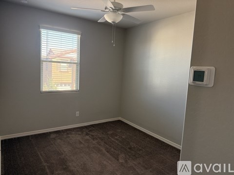 A room with a ceiling fan and a window with blinds.