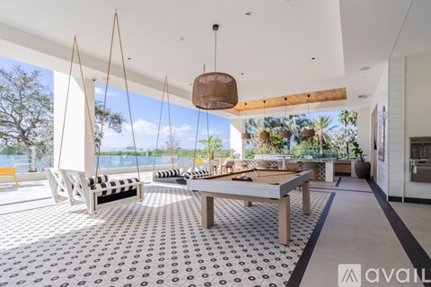 A modern outdoor living space with a pool table and hanging chairs.