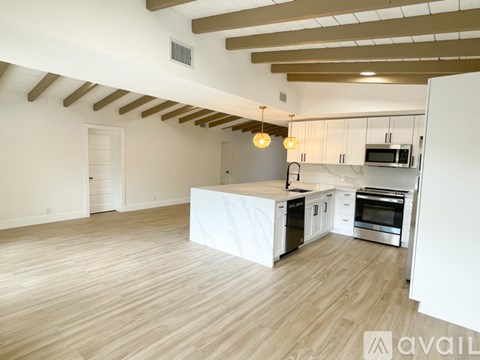 A spacious kitchen with white cabinets and a wooden floor.