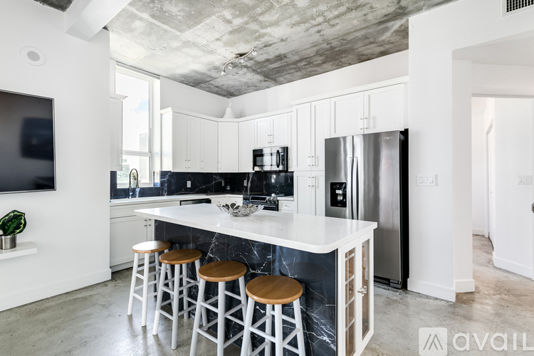A kitchen with a white countertop and bar stools.
