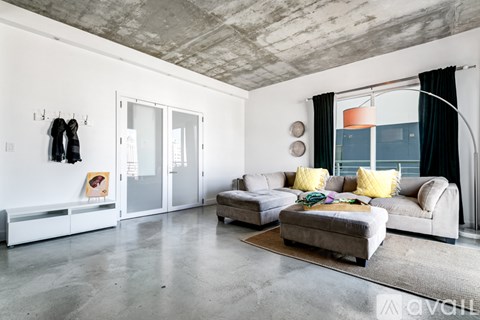 A modern living room with a grey couch and a grey ottoman.