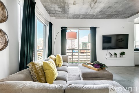 A modern living room with a grey couch and a large window.