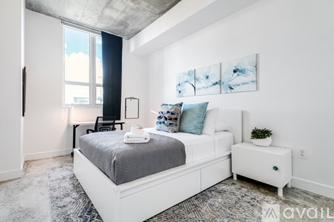 A bedroom with a large bed and a small white nightstand.