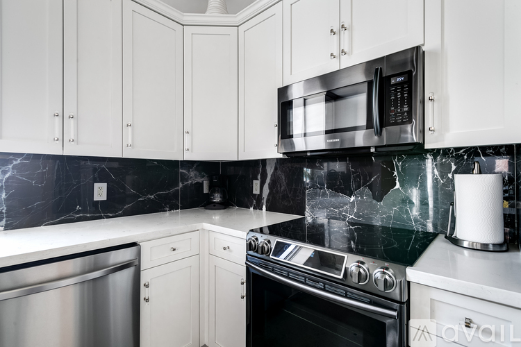 A kitchen with a black counter top and white cabinets.