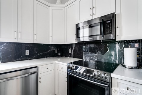 A kitchen with a black counter top and white cabinets.