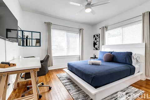 A bedroom with a blue bed and a white desk.