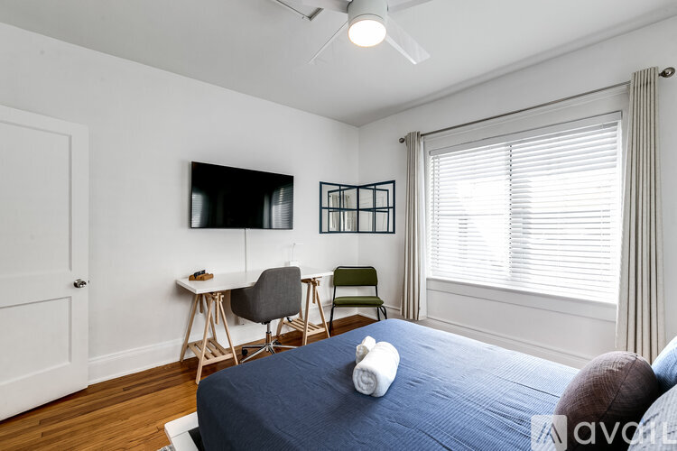 A bedroom with a bed, desk, chair, and window.