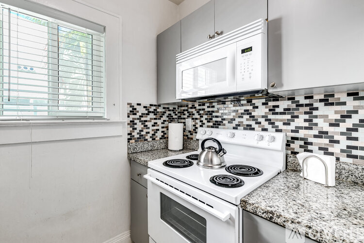 A white kitchen with a black and white tiled backsplash.