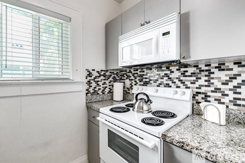 A white kitchen with a black and white tiled backsplash.