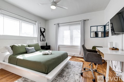 A bedroom with a bed, desk, and chair.