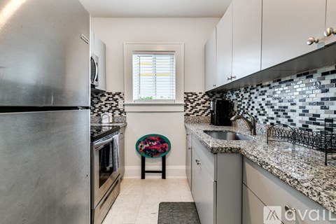 A kitchen with a stainless steel refrigerator and a black and white tiled backsplash.