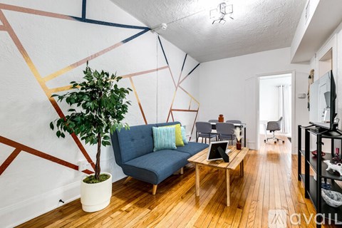 A living room with a blue couch and a potted plant.
