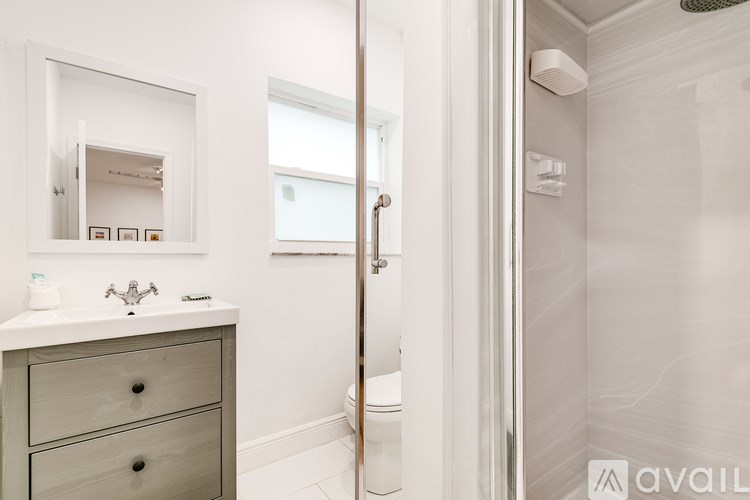 A bathroom with a white vanity and a walk-in shower.
