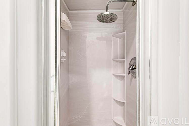 A shower with a white door and a white shower head.