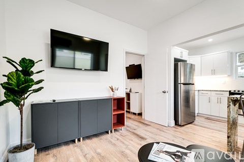 A living room with a tv on the wall and a plant in a pot.