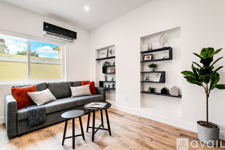 A living room with a grey couch, a small table, and a plant.