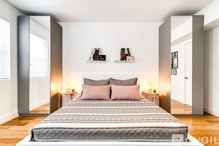 A bedroom with a bed, two pillows, and two lamps.