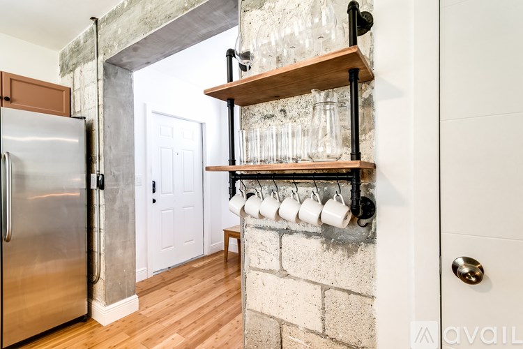 A kitchen with a refrigerator and a shelf with glasses on it.