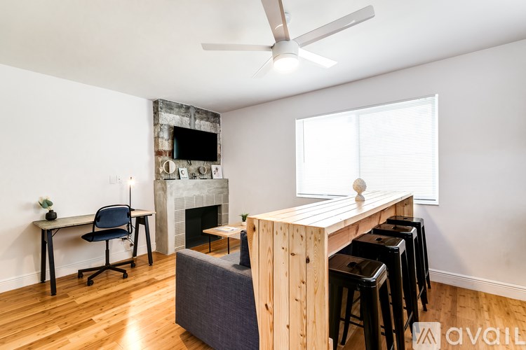 A room with a wooden table and chairs, a fireplace, and a ceiling fan.