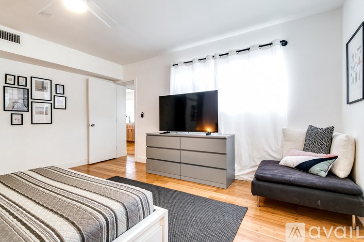 A bedroom with a bed, a couch, a dresser, and a television.