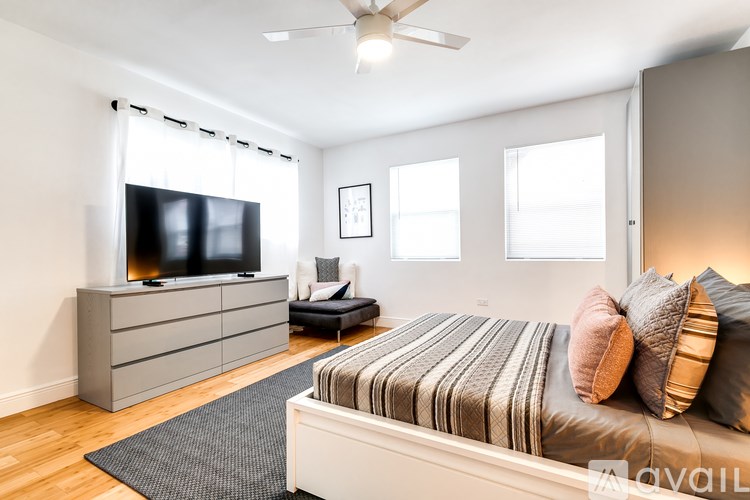 A bedroom with a bed, a television, and a ceiling fan.