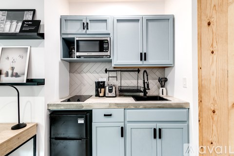 A kitchen with a black fridge and a black microwave above it.