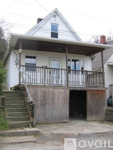 A white house with a balcony and stairs leading up to it.