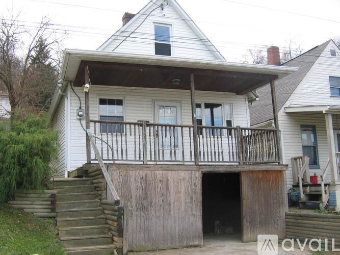 A white house with a balcony and stairs leading to a basement.