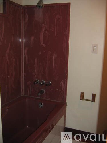 A red bathroom with a tub and a towel rack.