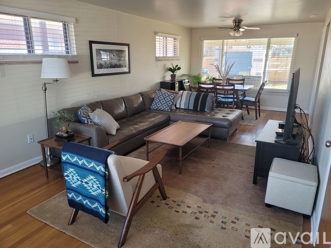 A living room with a brown couch, a wooden coffee table, and a blue and white throw blanket on a chair.