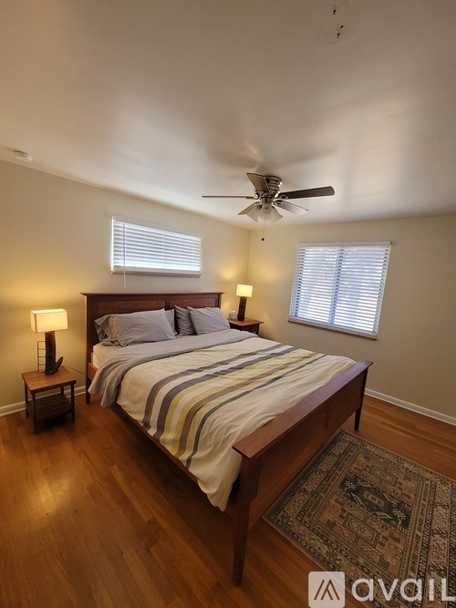 A bedroom with a bed, two lamps, and a ceiling fan.