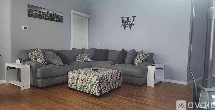 A living room with a grey couch and a patterned ottoman.