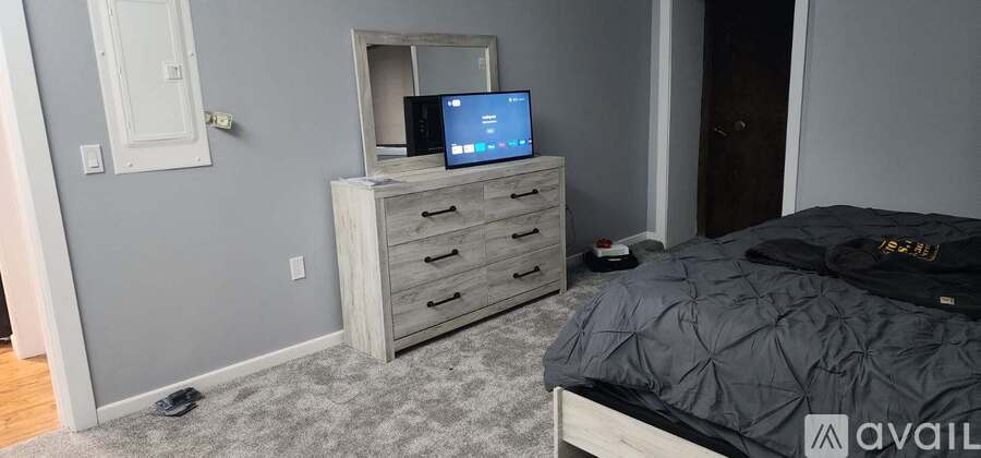 A bedroom with a bed, dresser, and mirror.