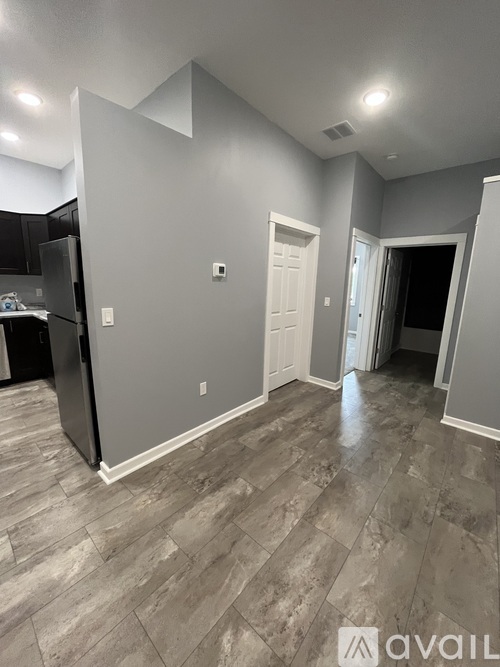 A kitchen area with a refrigerator and a door leading to another room.