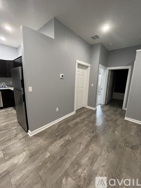 A kitchen area with a refrigerator and a door leading to another room.