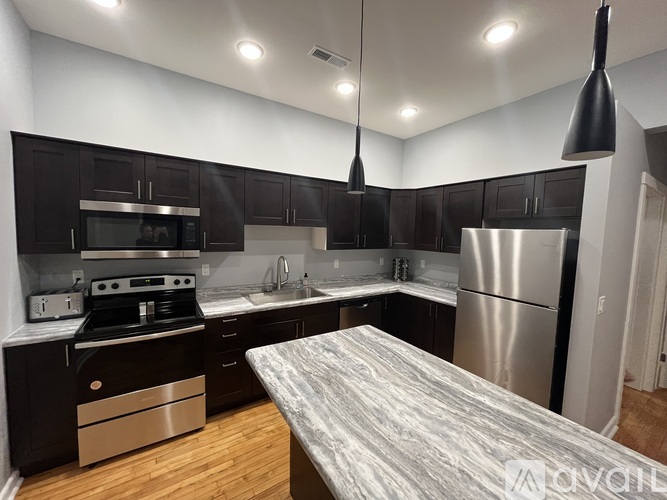 A modern kitchen with dark wood cabinets and stainless steel appliances.