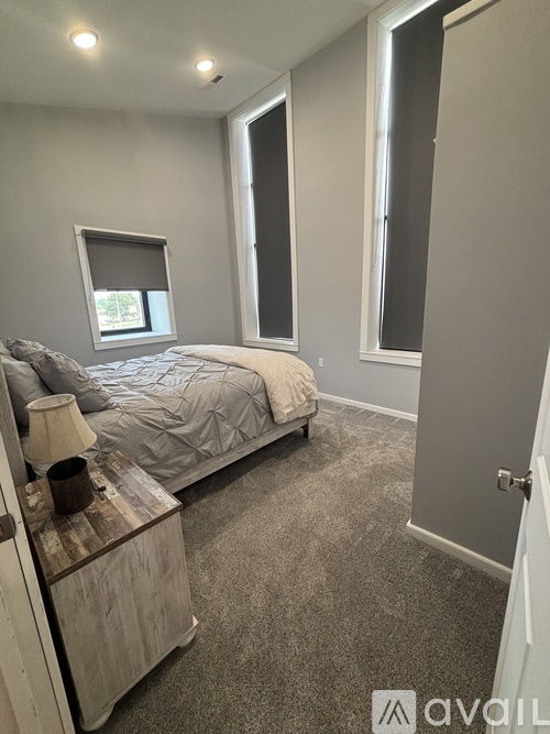 A living room with a grey carpet and a black couch.