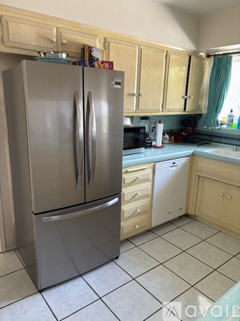 A kitchen with a stainless steel refrigerator and wooden cabinets.