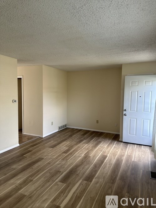 A room with a white door and wooden flooring.